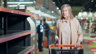 Süpermarkette son sınıf kadın alışverişçisi, boş rafların yanında bakkal. Yaşlı olgun kadın paniği satın alıp stokluyor. Biletleri tükenmiş erzak malzemeleri. Yiyecek kıtlığı.