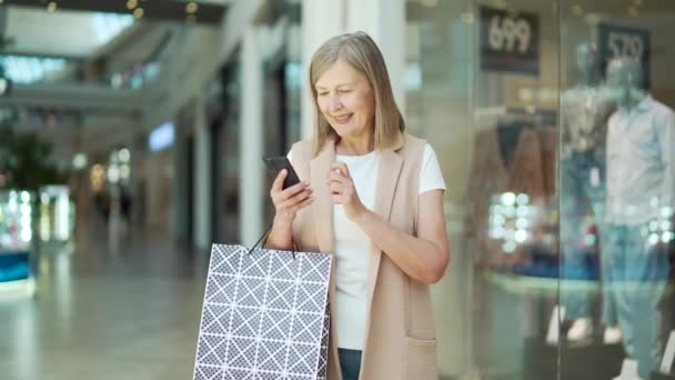 Senior Woman Dívá Mobilní Telefon Drží Nákupní Tašky Nákupním Centru — Stock video