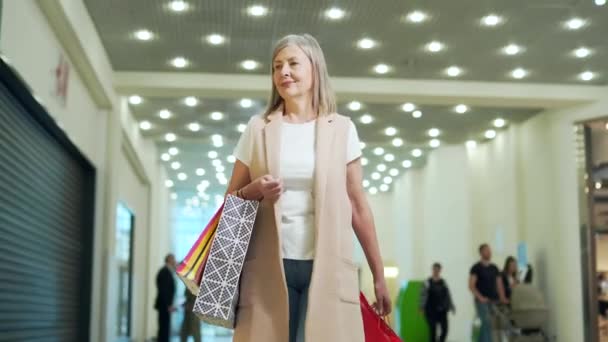 快乐的购物者 手里拿着包裹在商场里走来走去 超市里的白发老妇 满意的购物 去中心之间的商店 黑色星期五 — 图库视频影像