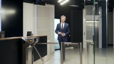Erkek işçi ofisteki otomatik güvenlik turnikesinden geçiyor. İşçi girişimci bu tarafa geçti. İş adamı iş merkezinin içine girer. Elektronik giriş kartını tutuyor