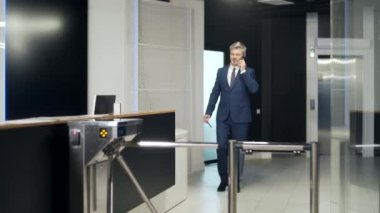 Erkek işçi ofisteki otomatik güvenlik turnikesinden geçiyor. İşçi girişimci bu tarafa geçti. İş adamı iş merkezinin içine girer. Elektronik giriş kartını tutuyor
