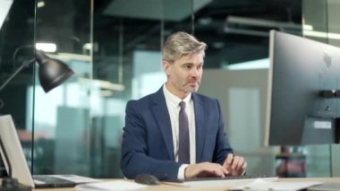 Bilgisayarda çalışan olgun sakallı işadamı çalışanı başarılı EVET Jesti 'ni kutluyor. Ilımlı ofiste çalışmak Şans Vuruşu, Büyük Kazanır. Kıdemli işçi zaferi İyi haber finansal anlaşma