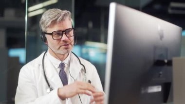 Hastanenin klinik reçetelerinde ya da ilaçlarında hastayla görüntülü görüşme yapan yaşlı, olgun bir erkek doktor. Deneyimli hekim danışmanlık hizmeti veriyor.