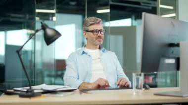 Olgun çalışanın işi bitti. Memnuniyetle ofis çalışanı arkasını yasladı. İşyerinde bilgisayar esneme işini bitirdikten sonra iş adamı dinleniyor.