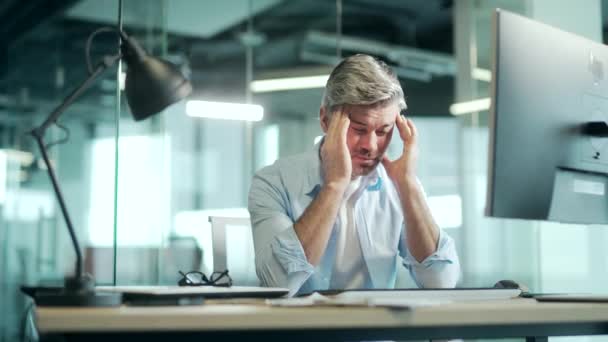 彼の頭をマッサージ厳しい頭痛で職場に座って疲れ 過労の成熟したオフィスの労働者 不健康な疲れた男性従業員痛み痛いです仕事でストレスセッションワーキングコンピュータ — ストック動画