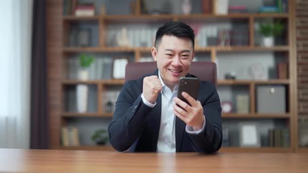 Gelukkige Jonge Aziatische Zakenman Het Kantoor Zoek Naar Mobiele Telefoon — Stockvideo