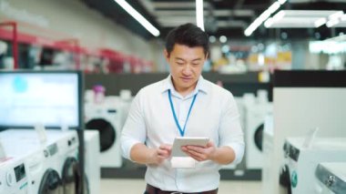 portrait smiling male asian sales consultant Expert who is standing in a home appliance store looking at camera. Employee Man worker seller smiles. salesman vendor with a tablet in his hands