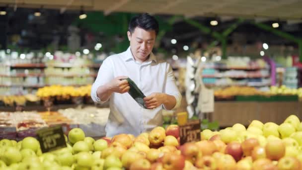 Young Asian Man Chooses Picks Eco Bag Apple Fruit Vegetables — Vídeo de stock