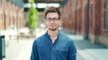 portrait handsome young male student in casual denim shirt and glasses looking at camera on urban university campus background. outside. Happy glad stylish caucasian guy. cheerful smiling, laughing