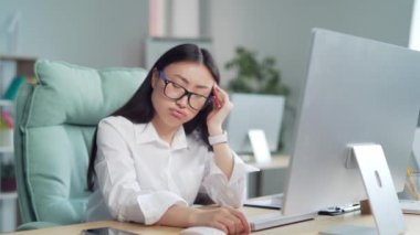 Exhausted, overworked asian office worker sitting in the workplace with severe headache massaging his head. unhealthy Tired female employee in pain ache sick Stress sedentary working computer. Asia