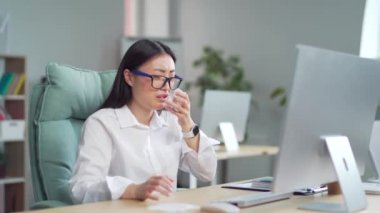 Sick young asian businesswoman coughing in office workplace. Employee entrepreneur worker indoor feeling unwell have a sore throat and chest. Unhealthy business female working on computer at desk