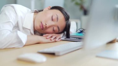 Yorgun Asyalı iş kadını ofis çalışanı ya da iş yerinde uyuyan tezgahtar. Aşırı yüklenmiş iş kadını çalışanı masaüstünde uyuyakalıyor. İş yerindeki masaüstünde çok çalışan yorgun bir kadın. Asya