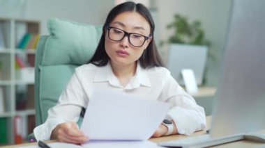 Difficult asian woman employee to deal with paperwork. documents. Stressed pensive businesswoman confused by mistake, thinking, looking papers. bookkeeper, booker vaguely, dimly at work in office