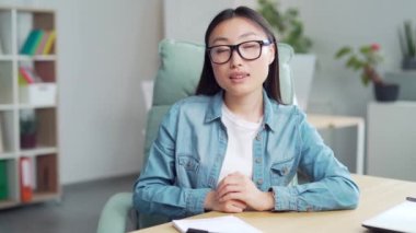 Young beautiful Asian woman listen on video call online, business woman working in modern office, coaching looking at web camera, online conference, meeting or interview webcam view remote startup