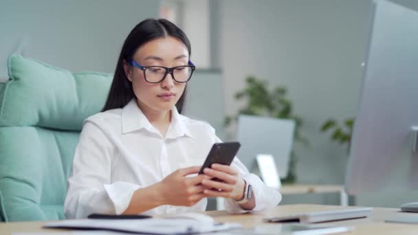 Happy Asian Business Woman Employee Entrepreneur Uses Smartphone Sitting Workplace — ストック動画