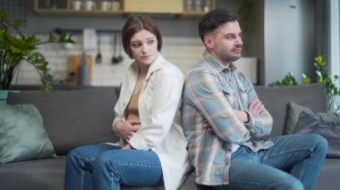 Family conflict. Young couple, pregnant woman and man sitting on sofa at home with their backs to each other. Do not talk, offended. spouses after a quarrel with a bad mood and misunderstanding