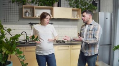 quarrel and misunderstanding in the family couple. A pregnant wife in a bad mood is screaming and arguing with her husband. angry woman at home in the kitchen during pregnancy. conflict man