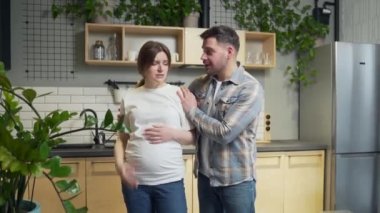quarrel and misunderstanding in the family couple. A pregnant wife in a bad mood is screaming and arguing with her husband. angry woman at home in the kitchen during pregnancy. conflict man