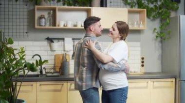 Man and pregnant woman dancing together, having fun at home, in the kitchen, happy family. Joyful romantic couple in love spending leisure time together. relax and listen to music during pregnancy