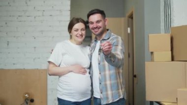 Portrait proud young happy family expecting a baby. Pregnant woman and husband owners couple holding keys standing in own new apartment. Smiling a home looking at camera. mortgage investment concept