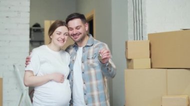 Portrait proud young happy family expecting a baby. Pregnant woman and husband owners couple holding keys standing in own new apartment. Smiling a home looking at camera. mortgage investment concept