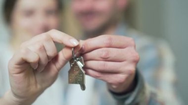 close up of the hands happy married couple holding keys to a new apartment. family bought a house together, hugging and looking at camera. concept of buying a home, loans, dwelling. Closeup