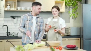 Happy young married couple, a pregnant wife and husband prepare lunch or breakfast together from vegetables. They feel fun, the family cooks in the kitchen during pregnancy and spends time together