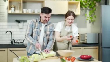 Portrait of young happy family man and pregnant woman together in the kitchen preparing healthy food, rejoicing and smiling couple cooks during pregnancy and spends time together