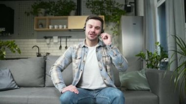 young man in casual clothes talking online on video call, remote meeting or conference, learning webcam view. Portrait of male at home conversation looking at camera waving his hand. indoor