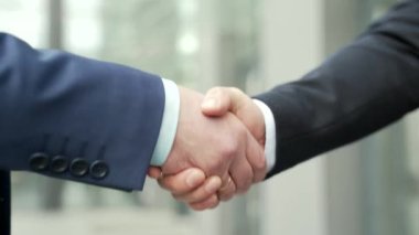 Close up business people shaking hands partnership deal while standing outside on the street near a big office building urban street. handshake closeup outdoor mature asian businessmen in formal suits