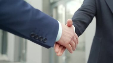 Close up business people shaking hands partnership deal while standing outside on the street near a big office building urban street. handshake closeup outdoor mature asian businessmen in formal suits