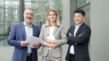 Group employees, entrepreneurs smile background office building outside. portrait team mature university or college teachers. lecturers or professors in formal suits. Business people looking at camera