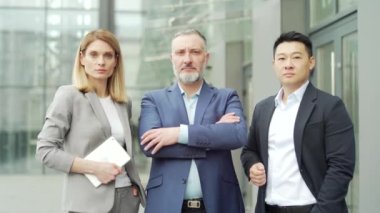 portrait of multiracial confident professional team of business people, businessmen employees in formal suits looking at camera. Group office workers outside Asian man, Caucasian woman and mature male