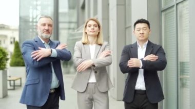 portrait of multiracial confident professional team of business people, businessmen employees in formal suits looking at camera. Group office workers outside Asian man, Caucasian woman and mature male