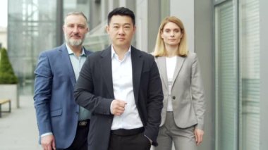 portrait of multiracial happy professional team of business people, businessmen employees in formal suits looking at camera. Group office workers outside Asian man, Caucasian woman and mature male