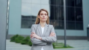 portrait attractive serious confident business woman employee looking at camera. Caucasian female blonde middle-aged worker stand near urban office building outside outdoor proud arms crossed