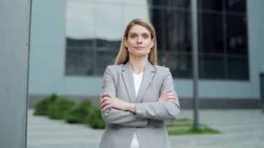 portrait attractive happy business woman employee looking at camera smiling. Caucasian female blonde middle-aged worker stand a city street near urban office center outside outdoor proud arms crossed