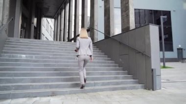 rear view Business woman employee climbs up stairs the step. To office center outside. Businesswoman goes to work. female office worker in a formal suit walks ascending staircase modern urban building