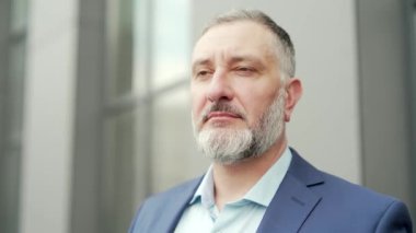 close-up portrait mature gray haired bearded businessman. Serious Looking at camera on urban background business center outside. outdoor Proud successful man Boss employee entrepreneur in formal suit