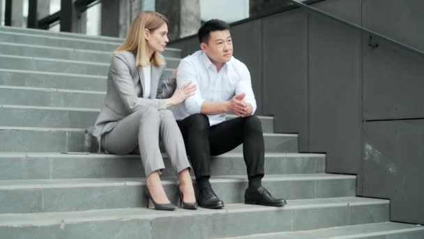 Asian Male Employee Supports Upset Depressed Female Worker Colleague Sitting — Stock Video