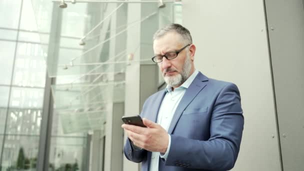 Serious Thoughtful Business Man Uses Smartphone While Standing Office Building — Stock Video