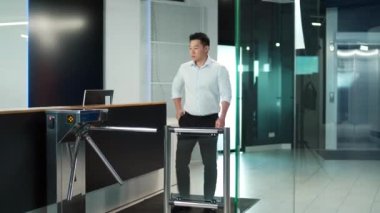 Erkek işçi ofisteki otomatik güvenlik turnikesinden geçiyor. Çalışan girişimciler birlikte çalışma alanından geçtiler. İçerideki iş merkezine girin. Elektronik giriş kartını tutuyor