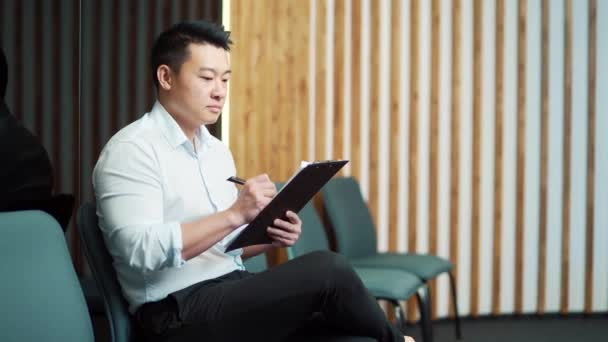Genç Asyalı Erkek Görüşmesi Görüşme Için Bekleme Odasında Sandalyede Otururken — Stok video