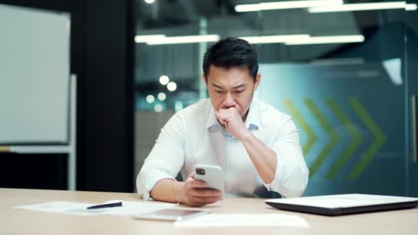 Preocupado Empleado Oficina Asiática Leyendo Malas Noticias Usando Teléfono Inteligente — Vídeos de Stock