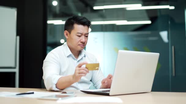 アジアのビジネスマンは オフィスのラップトップコンピュータでオンライン決済の失敗を作ります 男性労働者はクレジットカードでは問題がありません 従業員は取引を完了できませんでした — ストック動画
