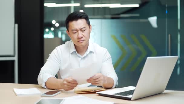 忧心忡忡的亚洲企业家读了一封有坏消息的信 惊慌失措的商人被拒绝了 男性经理员工在工作场所拆开银行通知 法律秩序文件 — 图库视频影像