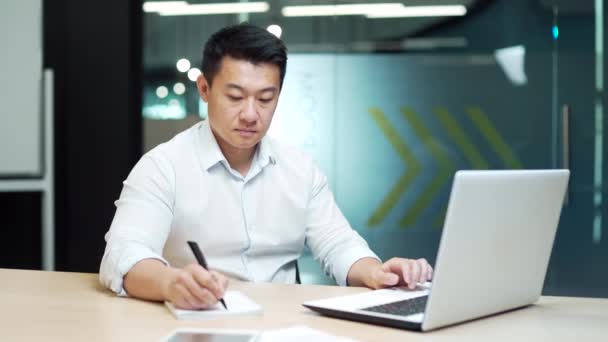 ウェブセミナーをオンラインで見ることに焦点を当てたビジネスマン アジアのビジネスマンはオフィスで遠隔でビデオトレーニングコースを研究しています コンピュータを使った遠隔教師やコーチとのバーチャルチャットミーティング — ストック動画