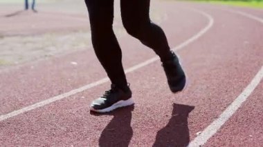Atletizm stadyumunda koşan bir koşucunun bacakları. Dışarıda yavaş çekimde koşuya yakın çekim. Yarış pistinde antrenman yapmak. Ayaklarını kapatıyordu.. 