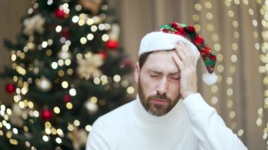 Yılbaşı partisini akşamdan kalma bir şekilde kutladıktan sonra başı ağrıyan bir adamın portresi. Mide bulantısı olan ve Noel ağacının arka planında evde sağlık sorunu olan bir erkek.