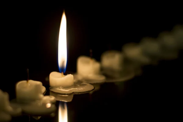 Vela encendida solitaria entre un grupo de velas extinguidas — Foto de Stock
